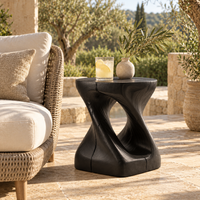 Black sculptural side table next to an accent chair