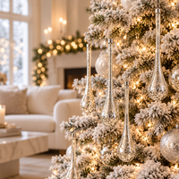 Silver teardrop ornaments hanging on a lit Christmas tree